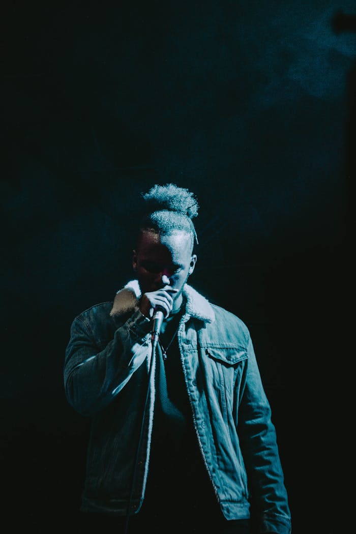 Dramatic image of a rapper performing under spotlight, wearing a stylish jacket, highlighting hip-hop culture.